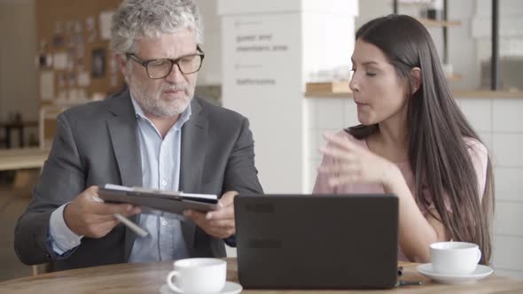 Grey-haired Senior Businessman Showing Points of Document