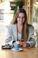 Smiling woman using the phone in a coffee shop. - PhotoDune Item for Sale