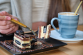 Unrecognizable woman eating a cake and drinking coffee in a cafe. - PhotoDune Item for Sale