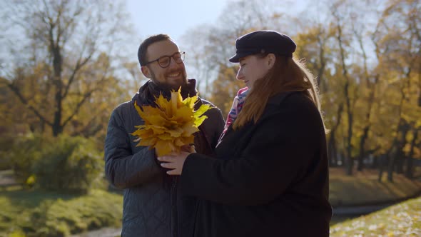 Loving Couple in Autumn Park with Maple Leaves Bouquet