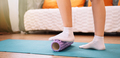 Lady massaging her foot with a purple massage roller on a fitness mat - PhotoDune Item for Sale