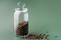 Glass jar with coffee beans on green background - PhotoDune Item for Sale