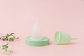 White menstrual cup on green podium and green one on pink background - PhotoDune Item for Sale