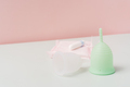 Menstrual cups with pads and tampon on white table against pink background - PhotoDune Item for Sale