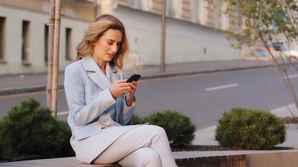 Young Beautiful Caucasian Business Woman Student Sitting Outdoors in City Background of Street