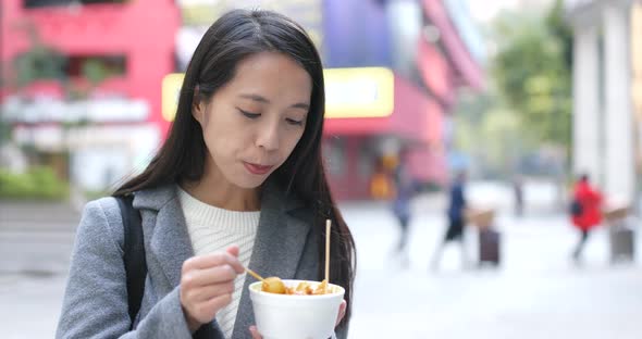 Businesswoman enjoy fish ball at street