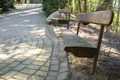 wooden benches in the park near a paved walking path with sunbeams - PhotoDune Item for Sale
