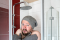 Man in a hat and mittens in the shower under cool water. Concept of energy crisis and savings. - PhotoDune Item for Sale