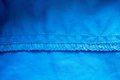 Overlock seam on blue fabric. Textured cloth background. Place for text. Flatley. - PhotoDune Item for Sale