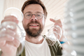 Camera view from the kitchen cabinet of a cute smiling man putting away clean wine glasses on shelf - PhotoDune Item for Sale