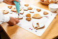 Woman decorating heart shaped cookies with frosting. Glazed festive homemade biscuits - PhotoDune Item for Sale