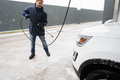 Man washing high pressure water american SUV car at self service wash in cold weather. - PhotoDune Item for Sale