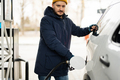 Man refueling his american SUV car at the gas station in cold weather. - PhotoDune Item for Sale