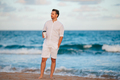 Young man in white with coffee on the beach walking and enjoy evening time - PhotoDune Item for Sale