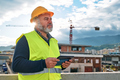 Middle aged bearded supervisor in hardhat and safety vest with tablet on building site. - PhotoDune Item for Sale