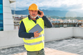 Middle aged bearded supervisor in hardhat with tablet talking worried on smartphone on building site - PhotoDune Item for Sale