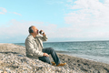 Bearded man listening music in headphones and drinking coffee while sitting on the beach. - PhotoDune Item for Sale