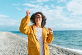 Smiling middle-aged female in headphones listening music and dancing while walking near the sea. - PhotoDune Item for Sale