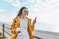 Smiling middle-aged female in headphones while walking near the sea. - PhotoDune Item for Sale