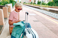 Blonde woman tourist using smartphone while waiting for train on railway station. - PhotoDune Item for Sale