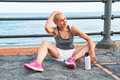 Fit woman relaxes on seaside promenade after running and training on a road by the sea. - PhotoDune Item for Sale