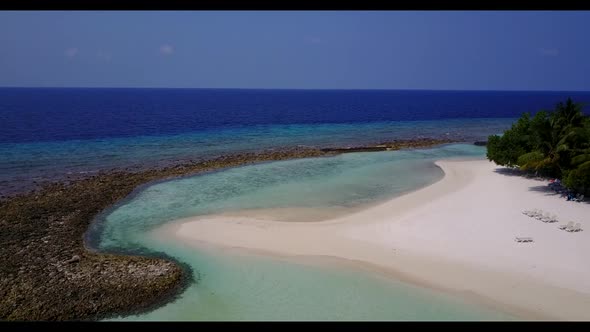 Aerial flying over scenery of luxury tourist beach lifestyle by blue ocean and white sandy backgroun