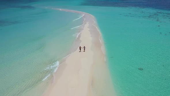 Loving couple running on sandy dune washed by turquoise seawater