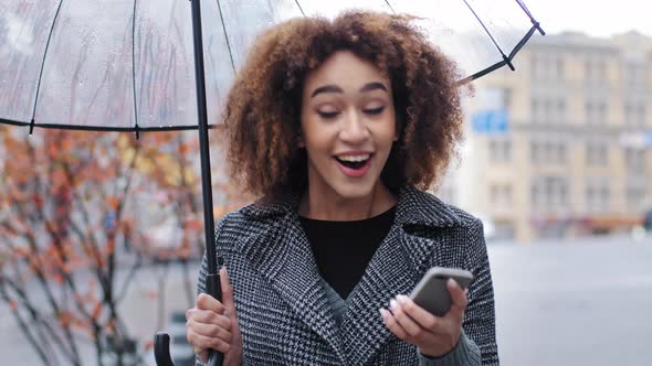African American Girl Curly Woman with Transparent Umbrella in Autumn Outdoors in Rain Wins with