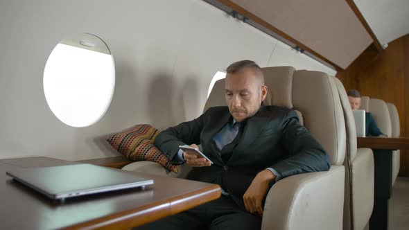 Confident Entrepreneur Traveling on His Private Jet and Chatting on Cell Phone.