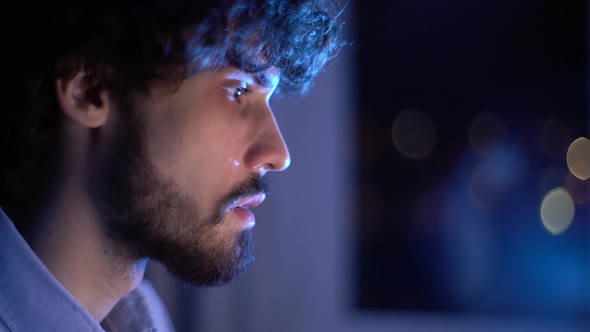 Closeup Face of Man Looking Intently at Monitor Screen While Working on Computer at Late Night