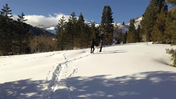 Couple snowshoeing through the forest on sunny day