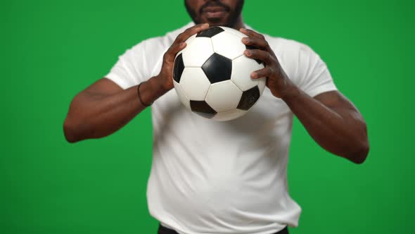 Unrecognizable Serious African American Footballer Holding Ball in Hands Standing at Chromakey