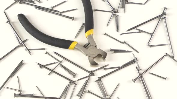 Wire Cutters with Yellow, Gray Handle on White Among Nails, Rotation