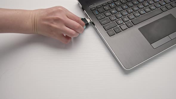 Female Hands Connected a USB Flash Drive to a Computer on a Light Background Closeup