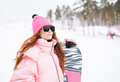 Young red haired woman in pink sportswear with snowboard on winter snowy background - PhotoDune Item for Sale