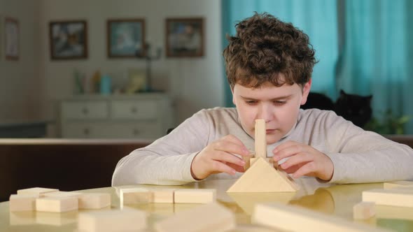 Caucasian preschool child plays with game cubes at a table in the living room.