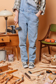 Cropped shot of unrecognizable handywoman wears denim overalls holds hammer does manual work in - PhotoDune Item for Sale