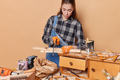 Skilled female carpenter cuts wooden plank with jigsaw produces wooden furniture for selling works - PhotoDune Item for Sale