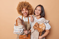 Horizontal shot of happy female bakers work together as team pose with loaves of freshly baked bread - PhotoDune Item for Sale
