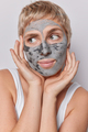 Headshot of serious thoughtful woman keeps hands on cheeks applies nourishing clay mask for skin - PhotoDune Item for Sale