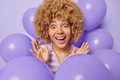 Optimistic cheerful woman with curly hair keeps hands raised up reacts to something awesome - PhotoDune Item for Sale