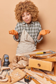 Hobby and carpenting concept. Clueless curly female carpenter shrugs shoulders looks with hesitation - PhotoDune Item for Sale
