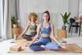 Yoga practice and meditation concept. Two women sit crossed legs on fitness mat breath deeply - PhotoDune Item for Sale