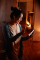 Happy Asian woman using cell phone and greeting someone while making video call at night at home. - PhotoDune Item for Sale
