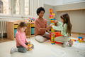 Happy black teacher and preschool kids playing with toy blocks in a playroom. - PhotoDune Item for Sale