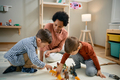 Small boys and their preschool teacher playing with toy animals on the floor. - PhotoDune Item for Sale