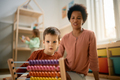 Small boy learning to count on abacus with his preschool teacher. - PhotoDune Item for Sale