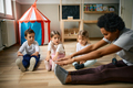 Group of kids and their teacher stretching during exercise class at preschool. - PhotoDune Item for Sale