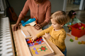 Small boy playing with wooden puzzle shapes with his teacher at kindergarten. - PhotoDune Item for Sale