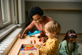Happy boy playing with colorful puzzle shapes with his kindergarten teacher. - PhotoDune Item for Sale